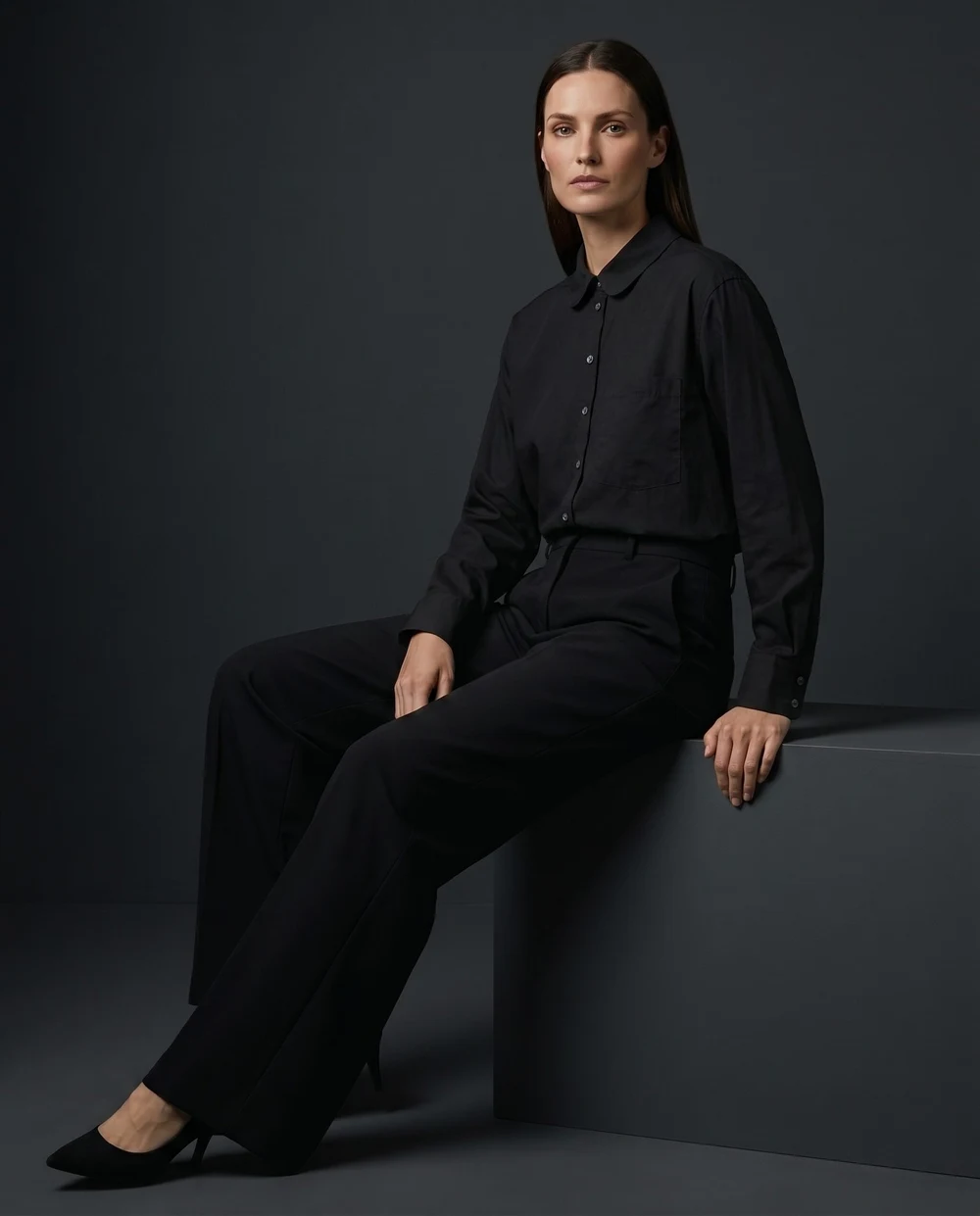The same black shirt worn by a model seated in a dark studio