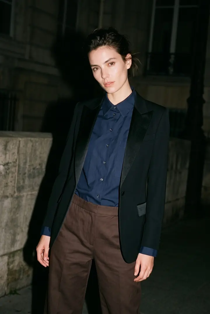 A model in a navy shirt and blazer on a street at night