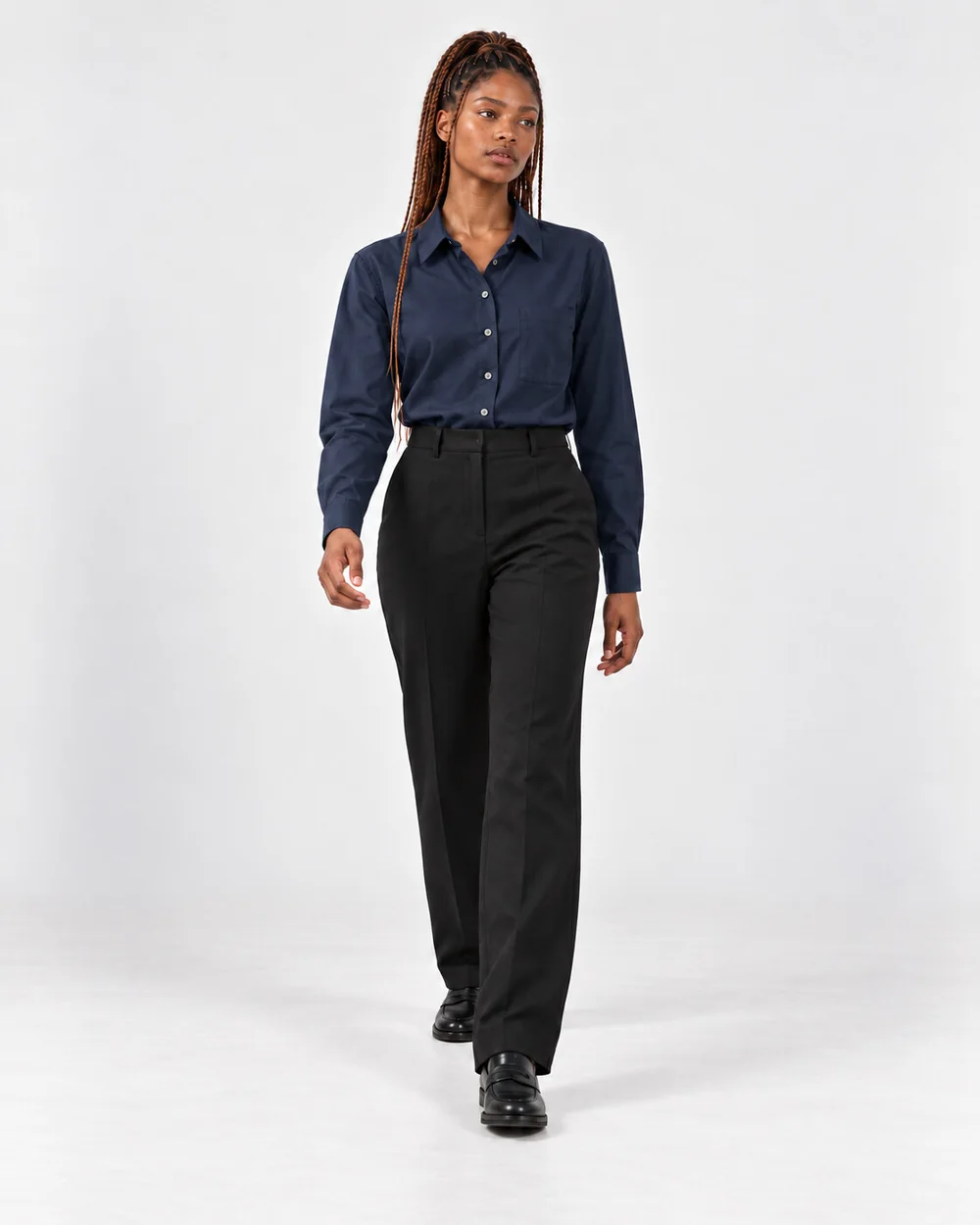 Ready-made model Zola walking in a navy shirt and black trousers, looking off to the side