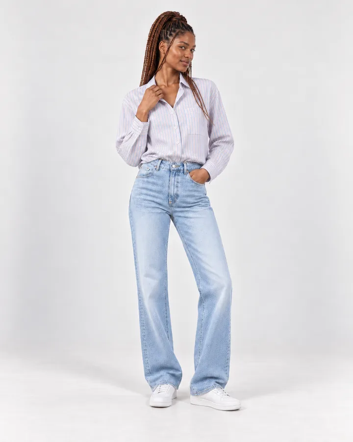 Ready-made model Zola in a pale striped shirt and light jeans, glancing back over her shoulder